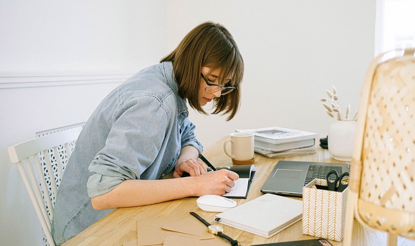une femme écrit des notes assise à un bureau