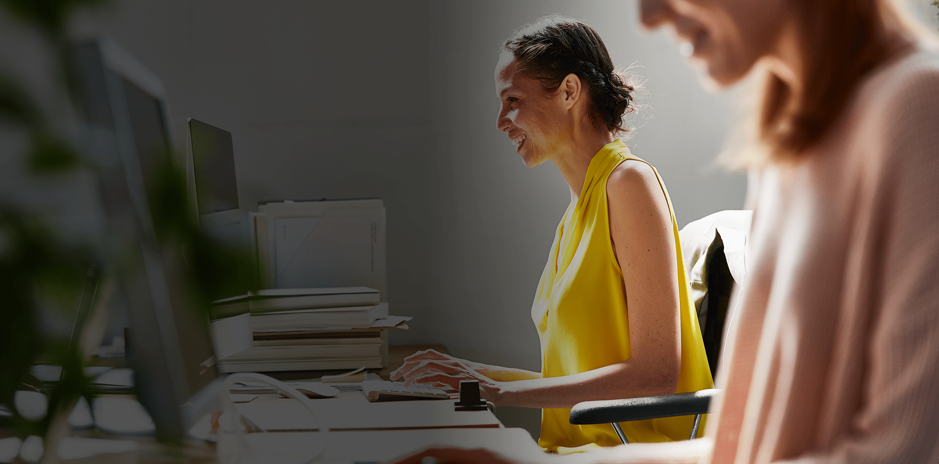 Deux femmes au bureau entrain d'utiliser des ordinateurs