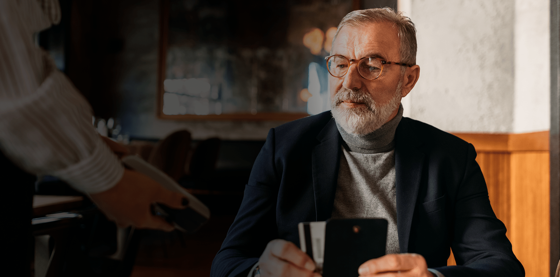 Homme d'affaires assis dans un bar paie avec une carte de banque