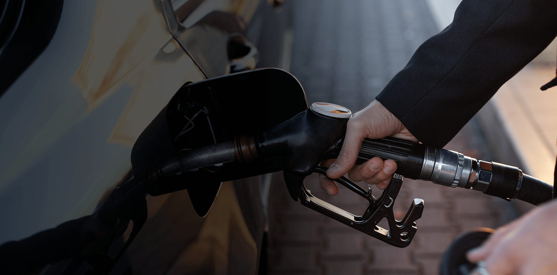 Zoom sur des mains entrain de mettre de l'essence dans une voiture via une pompe à essence
