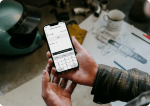 IT-Man holding an iPhone 13 Pro mockup over a mechanic work table (Mockuuups Studio)