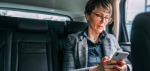 HMRC Travel Expenses. The image shows a woman travelling in a taxi looking at her phone.